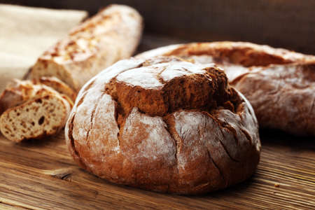 Different kinds of bread and bread rolls on board from above. Kitchen or bakery poster design.の写真素材