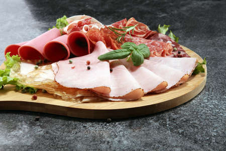 Food tray with delicious salami, pieces of sliced ham, sausage and salad. Meat platter with selectionの写真素材