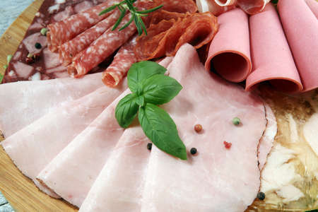 Food tray with delicious salami, pieces of sliced ham, sausage and salad. Meat platter with selectionの写真素材