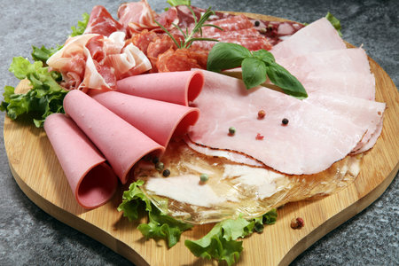 Food tray with delicious salami, pieces of sliced ham, sausage and salad. Meat platter with selectionの写真素材