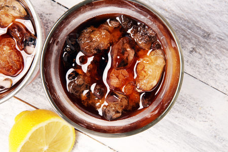 Softdrink with ice cubes, lemon and straw in glass.の写真素材