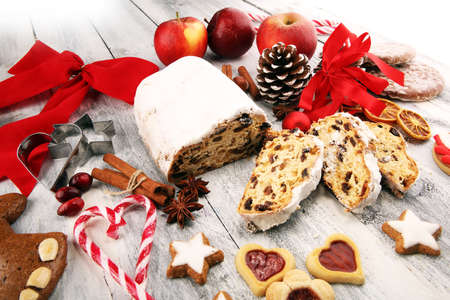 Traditional European Christmas pastry, fragrant home baked stollen, with spices and dried fruit. Sliced on rustic table with xmas tree branches and decorations.の写真素材