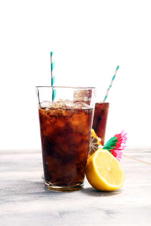 Softdrink with ice cubes, lemon and straw in glass.の写真素材