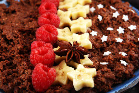 Bowl of cacao oatmeal porridge with banana, raspberries coconut and caramel sauce on rustic table, hot and healthy food for Breakfast.の写真素材