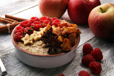 Bowl of oatmeal porridge with banana, apples,raspberries coconut and caramel sauce on rustic table, hot and healthy food for Breakfast.の写真素材