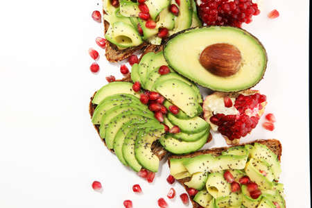 sliced avocado and ripe pomegranates on toast bread with spices and avocado の写真素材