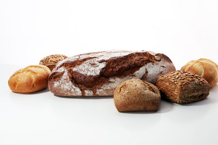 Different kinds of bread and bread rolls on board from above. Kitchen or bakery poster design.