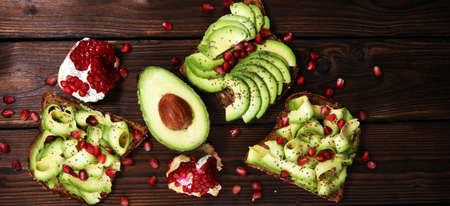 sliced avocado and ripe pomegranates on toast bread with spices and avocado の写真素材