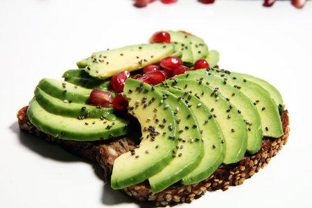 sliced avocado and ripe pomegranates on toast bread with spices and avocado