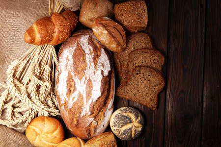 Different kinds of bread and bread rolls on board from above. Kitchen or bakery poster design.の写真素材