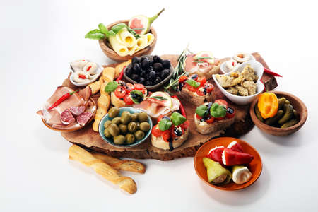 Italian antipasti wine snacks set. Cheese variety, Mediterranean olives, pickles, Prosciutto di Parma, tomatoes, artichokes on tableの写真素材