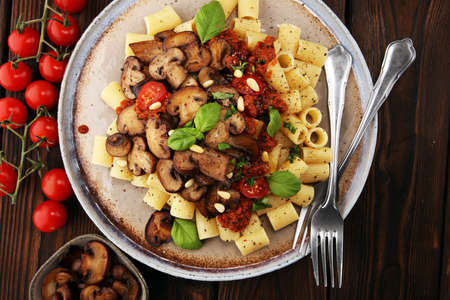Penne pasta rigatoni in tomato sauce with mushrooms, tomatoes decorated with parsley and basilの写真素材