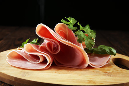 Sliced ham with parsley on table. Fresh prosciutto. Pork ham sliced snackの写真素材