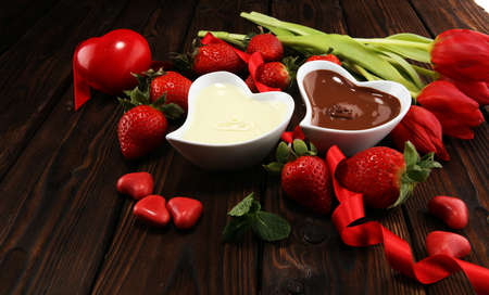 Valentine Chocolate fondue melted with fresh strawberries and dark and white chocolate. Tublips and red sugar heartsの写真素材