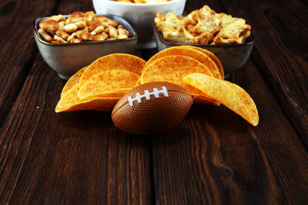 Chips, salty snacks, football on a table. Great for Bowl Game.の写真素材