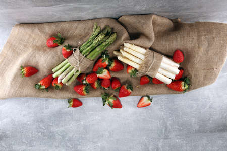 White and green fresh asparagus with a bunch of healthy strawberriesの写真素材