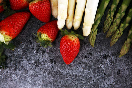 White and green fresh asparagus with a bunch of healthy strawberriesの写真素材