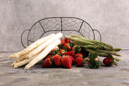 White and green fresh asparagus with a bunch of healthy strawberriesの写真素材