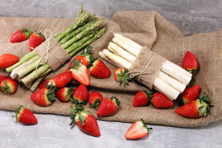 White and green fresh asparagus with a bunch of healthy strawberriesの写真素材