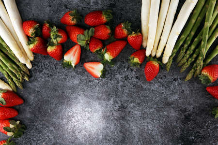 White and green fresh asparagus with a bunch of healthy strawberriesの写真素材