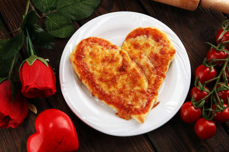 Valentines day pizza in heart shape on dark rustic wooden background.  Valentine heart pizza foodの写真素材