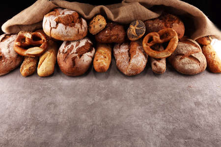 Assortment of baked bread and bread rolls on stone table background. Bakery poster conceptの写真素材