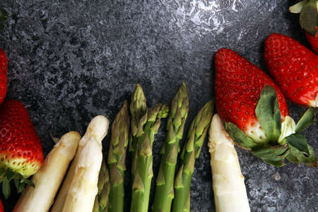 White and green fresh asparagus with a bunch of healthy strawberriesの写真素材