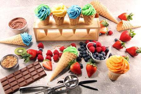 Vanilla frozen yogurt or soft ice cream in waffle cone. Different flavor ice cream with kiwi and...
