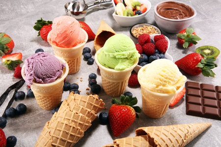 Set of ice cream scoops of different colors and flavours with berries, nuts and fruits and vanilla