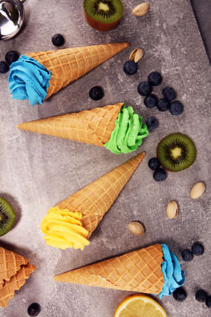Vanilla frozen yogurt or soft ice cream in waffle cone. Diffrent flavor ice cream with kiwi and pistachio, mango and lemon, blueberry and blackberryの写真素材