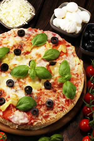 Delicious pizza with pineapple, ham slice, bacon slice, mozzarella cheese, pizza sauce on rustic background for fast food and ready to eat concept. pizza hawaiiの写真素材