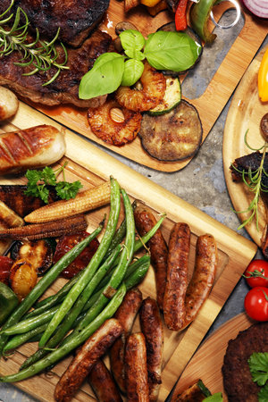 Assorted delicious grilled meat with vegetable and herbs on rustic table