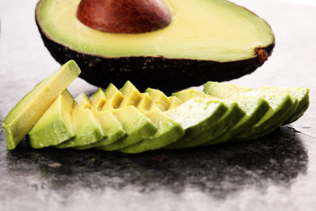 Avocado on old table. Halfs of fresh ripe hass avocado. Fruits healthy food concept