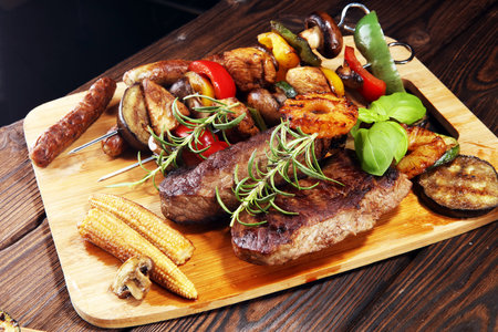 Assorted delicious grilled meat with vegetable and herbs on rustic table