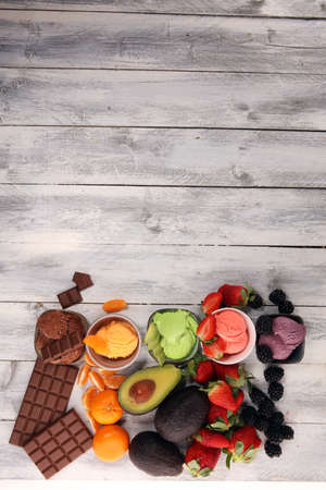 Set of ice cream scoops of different colors and flavours with berries, chocolate and fruits on tableの写真素材