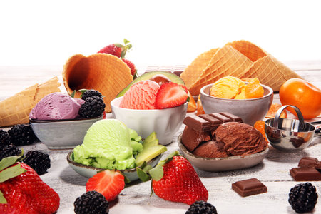 Set of ice cream scoops of different colors and flavours with berries, chocolate and fruits on table