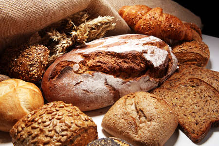 Different kinds of bread and bread rolls on board from above. Kitchen or bakery poster design.の写真素材