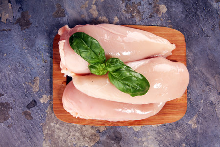 Raw chicken breasts and spices on wooden cutting board, close up view. Healthy chickenの写真素材