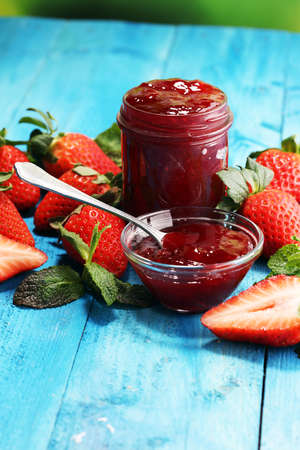 strawberry jam with fresh strawberries. marmalade on spoon and jar on blue backgroungの写真素材