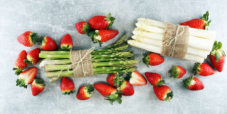 White and green fresh asparagus with a bunch of healthy strawberriesの写真素材