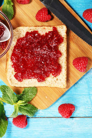 Toast bread with homemade raspberry jam or marmalade on rustic blue table served with butter for breakfast or brunchの写真素材