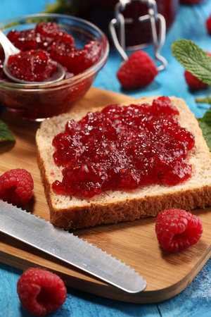 Toast bread with homemade raspberry jam or marmalade on rustic blue table served with butter for...