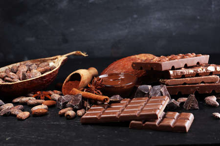 Melting chocolate or melted chocolate with a chocolate swirl and stack, chips and powder on dark tableの写真素材