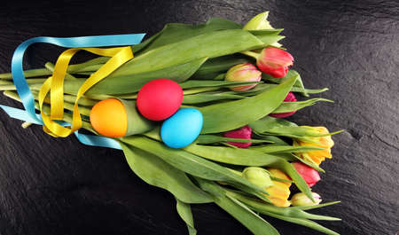 Easter eggs and colorful tulips on rustic tableの写真素材