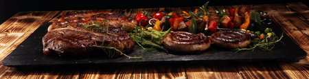 Assorted delicious grilled meat with vegetable on a barbecue with t-bone steak and sausages