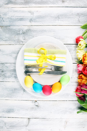Festive table setting for Easter with fork, knife and tulip on spring