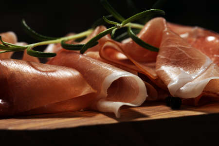 Italian prosciutto crudo or jamon with rosemary. Raw ham on wooden backgroundの写真素材