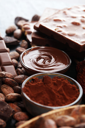 Melting chocolate or melted chocolate with a chocolate swirl and stack, chips and powder on dark...