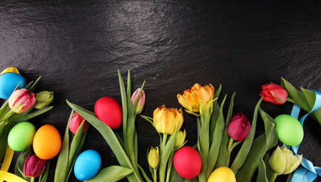 Easter eggs and colorful tulips on rustic tableの写真素材