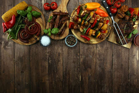Assorted delicious grilled meat and skewer with vegetable and herbs on rustic tableの写真素材